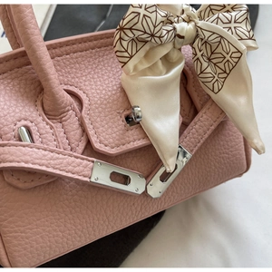 Detail der rosa Lederhandtasche mit Silberverschluss und dekorativem Seidentuch am Griff