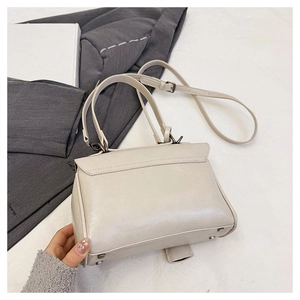 Detail of off-white leather bag showing metal feet and detachable adjustable shoulder strap