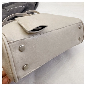 Detail of off-white lychee grain handbag with four protective metal feet and fine stitching
