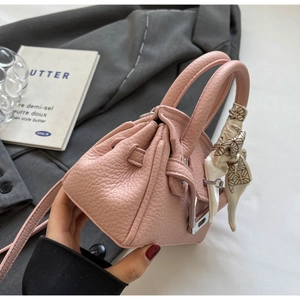 Detailansicht der rosa Handtasche mit Litschimuster, Seidenschal und silbernem Schloss