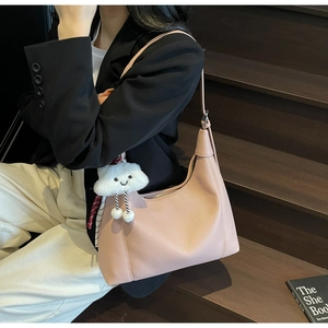 Close-up of pink pebbled leather hobo bag with cute white cloud plush pendant accessory