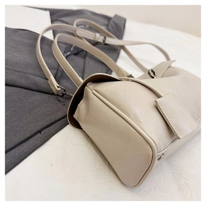 Detail view of the elegant beige leather handbag featuring a metal turn-lock and strap detail