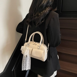 Trendy cream pillow bag with lace pearl charm shown as a stylish crossbody bag.