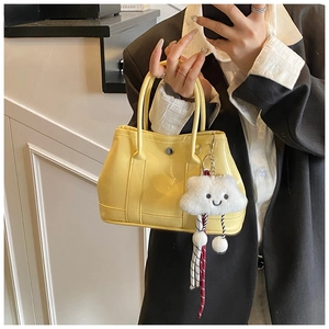 Detail of bright yellow bucket bag with glossy finish and cute white cloud charm