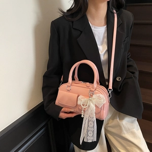 Pink glossy pillow bag with pearl lace bow charm shown on a stylish fashion model