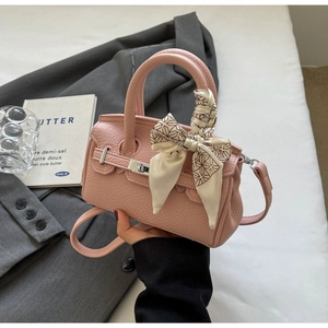 Detail der rosa Handtasche aus Leder mit dekorativem Seidentuch und silbernem Drehverschluss