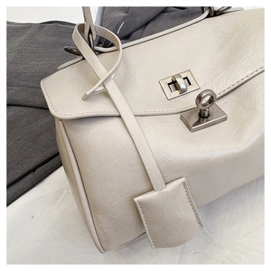 Detail of beige shoulder bag featuring dual silver square twist locks and precise stitching
