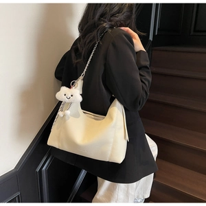 Detail of cream-white tote bag with lychee texture, silver chain and plush cloud charm