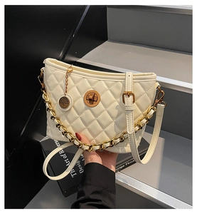 Detail of white quilted handbag featuring gold metal chain and rotary lock mechanism