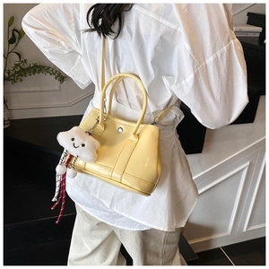 Detail of cream bucket bag with polished finish and a cute white cloud plush charm