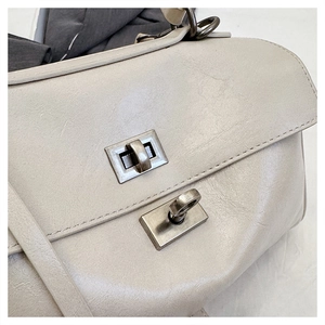 Macro shot of stylish creamy white leather bag with vintage metal turn-lock closure detail