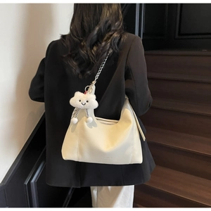 Detail of hobo tote bag with lychee texture and plush cloud charm on chain strap