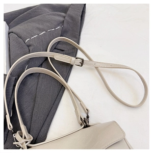 Detail of adjustable beige faux leather shoulder strap with dark gunmetal buckle