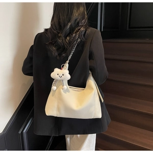 Detail of warm white hobo bag with silver chain strap and plush cloud charm on leather