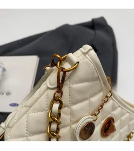 Detailed view of beige quilted leather texture and antique gold chain on the shoulder bag