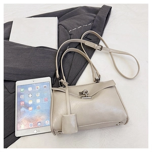 Close-up of beige leather handbag with silver twist lock and adjustable shoulder strap