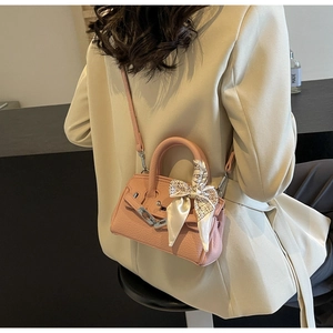 Detail der hellrosa Leder-Handtasche mit Seidenschal am Griff und Metallschnalle