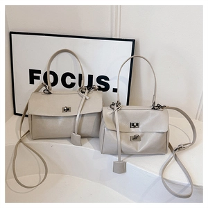 Detail view of beige crossbody bags in two sizes with metal locks on minimalist background