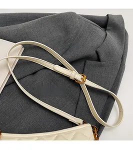 Detail of cream quilted handbag featuring adjustable strap with gold-tone metal buckle