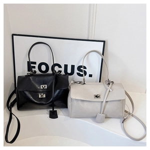 Detail of minimalist leather crossbody bags with metal twist locks in black and cream
