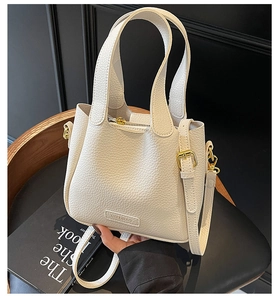 Detail of lychee pattern leather bucket bag in cream white with a metallic buckle strap