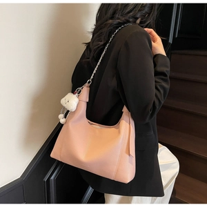 Detail of pink lychee leather hobo bag with silver chain strap and plush bear charm