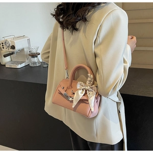 Detail einer rosa Lederhandtasche mit Seidentuch am Griff und Metallverschluss