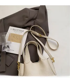 Detail of creamy white bucket bag with pebble leather texture and golden shoulder strap buckle