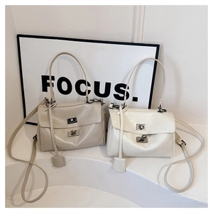 Detailed view of two vegan leather handbags with dual metal twist locks and top handles