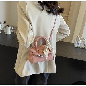 Detail der rosa Lederhandtasche mit bedrucktem Seidenschal am Griff und dem Metallschloss