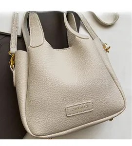 Close-up of off-white lychee grain leather bucket bag with gold hardware and brand logo
