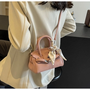 Detailansicht einer rosa Ledertasche mit dekorativem Seidenschal am Griff von hinten