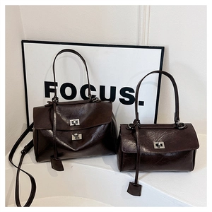 Detail of two dark brown glossy leather crossbody bags with silver metal turn-locks