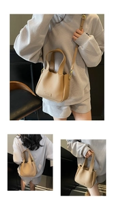 Detail view of khaki pebbled leather bucket bag showing dual handles and gold hardware