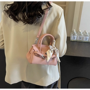 Detailansicht der rosa Ledertasche mit dekorativem Seidenschal am Griff und Riemen