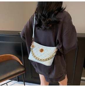Detail of baby blue quilted crossbody bag with gold chain and metal twist lock