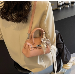 Details der rosa Handtasche aus Leder mit dekorativem Schal und silbernem Drehschloss
