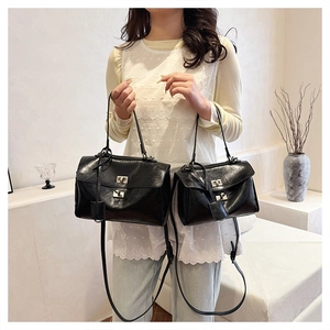 Detail showing two sizes of glossy black shoulder bags with silver metal turn-lock closures