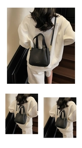 Detail of black litchi grain bucket bag with gold hardware and dual handles