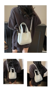 Detail of light blue lychee pattern leather bucket bag with dual handles and brand logo