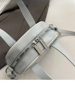 Detail of smooth double silver metal zippers on light blue round leather crossbody bag