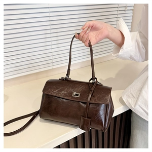 Detail of dark brown vintage oil wax leather handbag with silver metallic twist lock