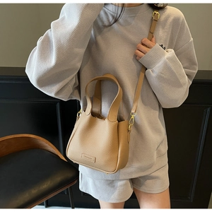 Detailed shot of the light khaki bucket bag with lychee texture and golden hardware