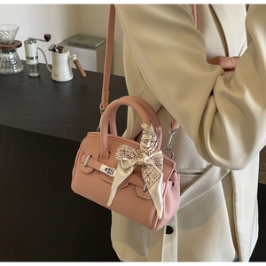 Detail einer rosa Handtasche aus Litschi-Leder mit gemustertem Seidenschal am Griff