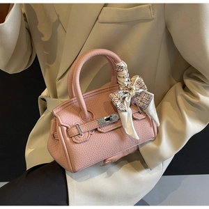 Nahaufnahme der rosa Handtasche aus Leder mit dekorativem Seidenschal am runden Griff