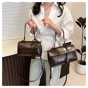 Detail of dark brown vintage faux leather bags in two sizes with smooth pleated texture