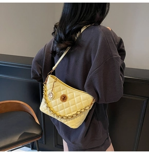 Close-up of bright yellow quilted crossbody bag with chunky chain and vintage lock detail
