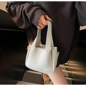 Close-up of light blue litchi grain leather bucket bag with top zipper and embossed logo
