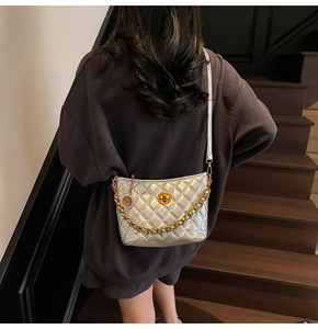 Detail of silver quilted crossbody bag featuring gold chain and turn-lock closure