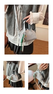 Detail view of small square shoulder bag with bear pendant and YAZIANDI logo in a cafe